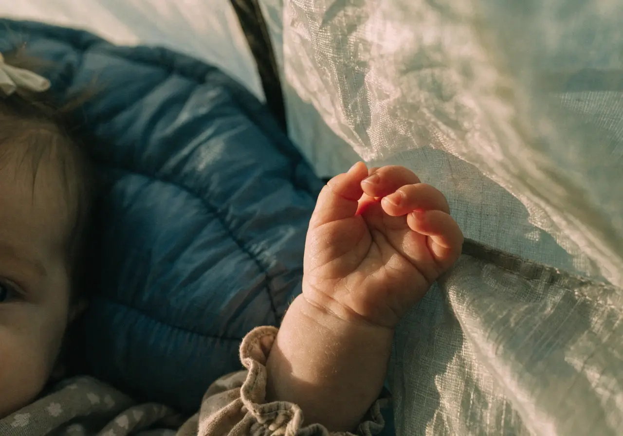 Parent and baby sitting outside a tent at a campsite