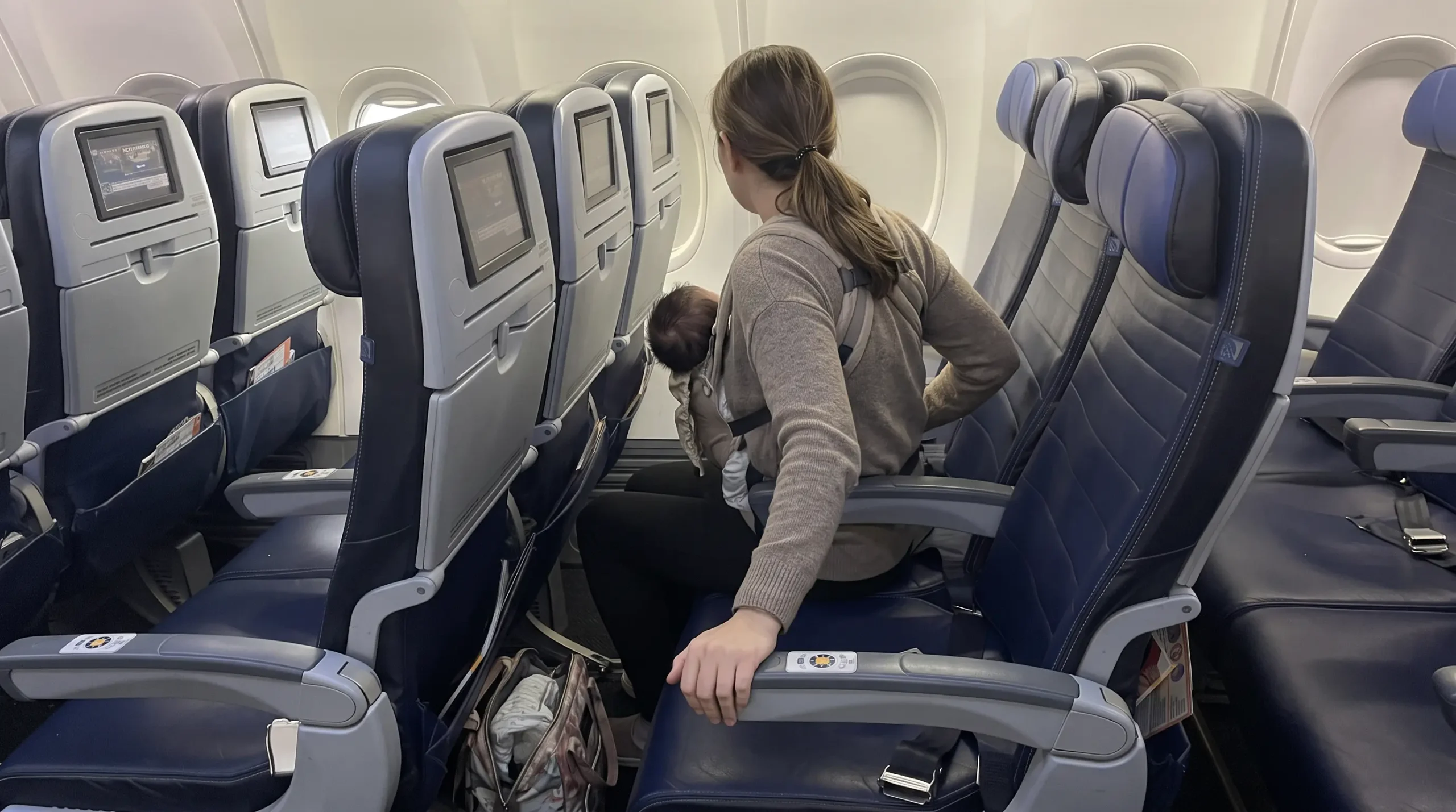 Parent boarding a United Airlines flight with a baby in a carrier