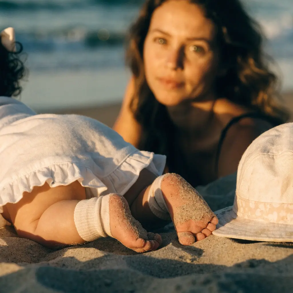 Baby lying in the shade of a beach umbrella on a sandy beach