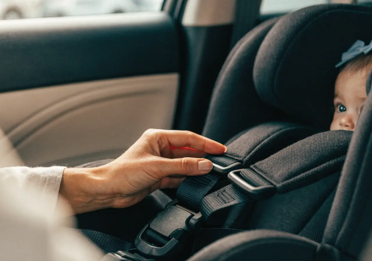 Parent and baby stepping out of a taxi with a car seat nearby